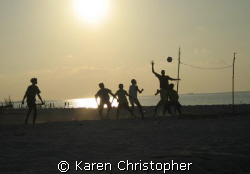 Young boys play volleyball with a makeshift "net" after t... by Karen Christopher 